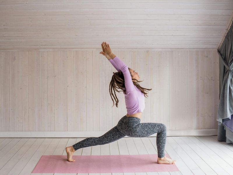 Woman performing a flowing yoga sequence in a minimalist studio.